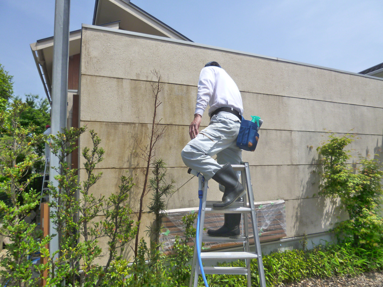 高所で外壁を掃除する男性